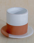 Ceramic cup with a white top and terracotta bottom on a beige background