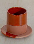 Ceramic cup and saucer set with a gradient color on a textured beige background