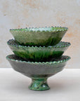 Authentic Tamegroute pottery bowl, handmade in the village of Tamegroute, southern Morocco. Every bowl is hand-thrown from local mineral-rich clay and finished with the village's signature deep green glaze. Fired in underground wood-fired kilns using centuries-old techniques, the heat creates natural variations in tone and texture across each piece. The glaze reacts organically to the kiln fire, producing distinctive emerald-to-moss tones with subtle bronze highlights. No two bowls are identical.
Perfect as