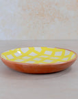 Ceramic plate with a yellow and white geometric pattern on a beige background