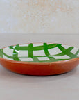 Ceramic plate with green and white pattern on a beige background