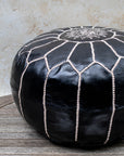 Black leather pouf beige stitching detail close up
