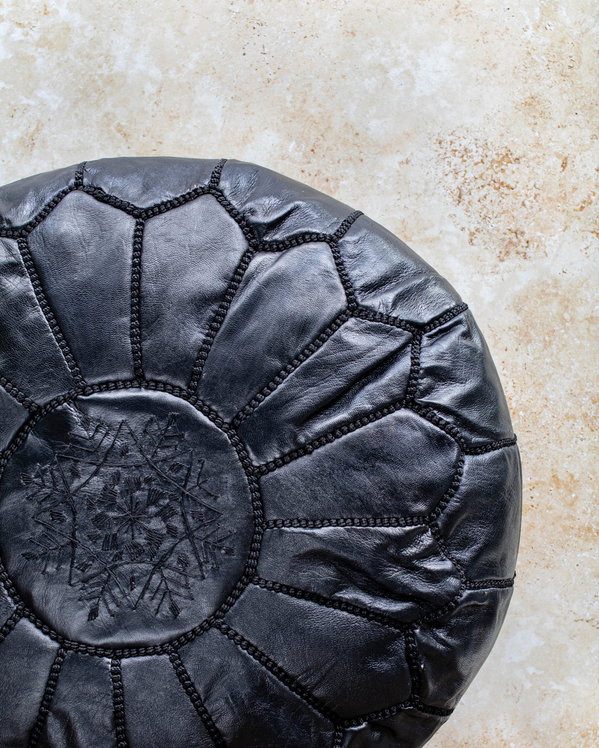 Black pouf styled in living room as ottoman