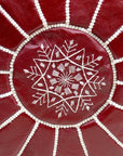 Burgundy pouf styled in living room as ottoman