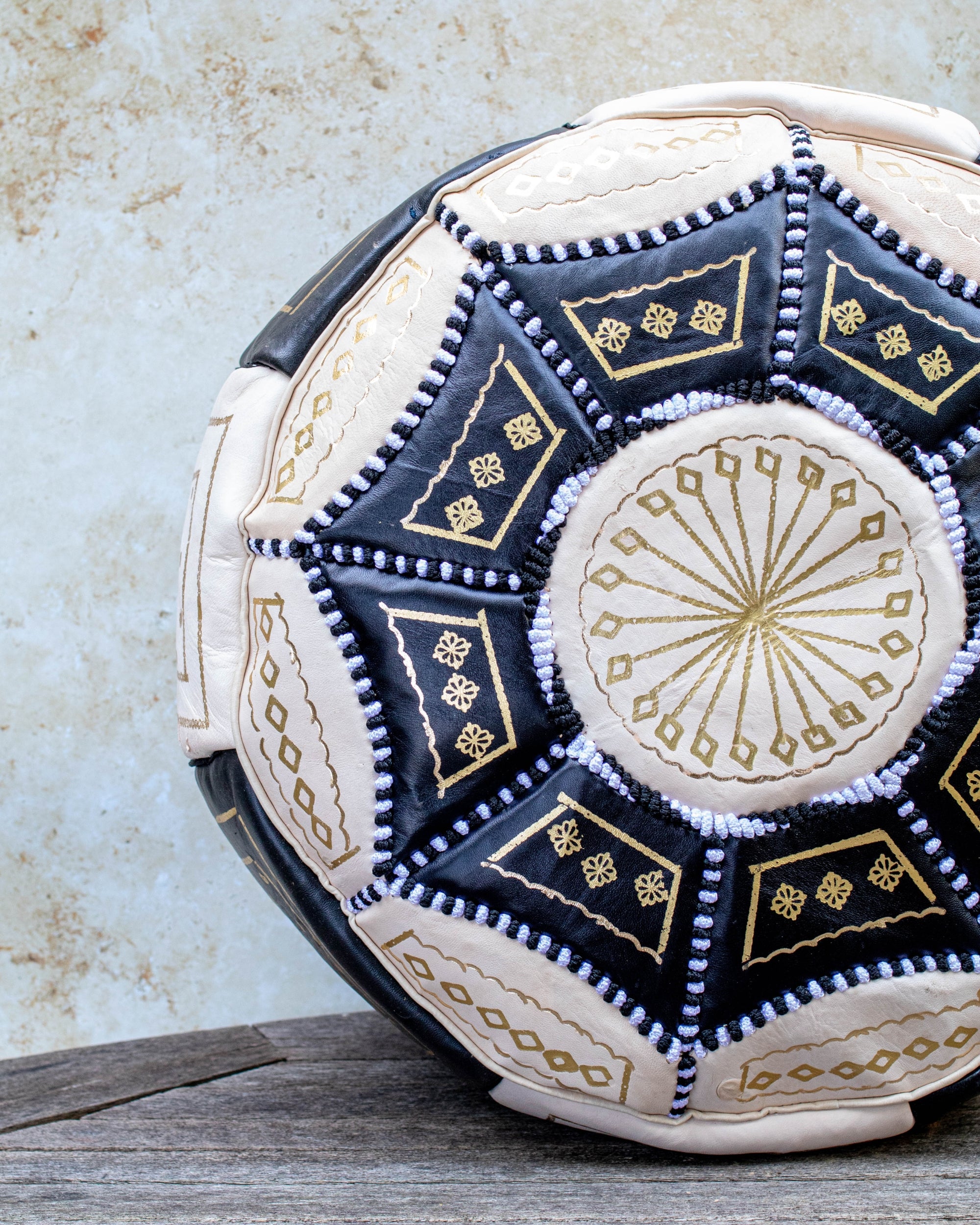 Close-up of gold embroidery on black and cream leather pouf