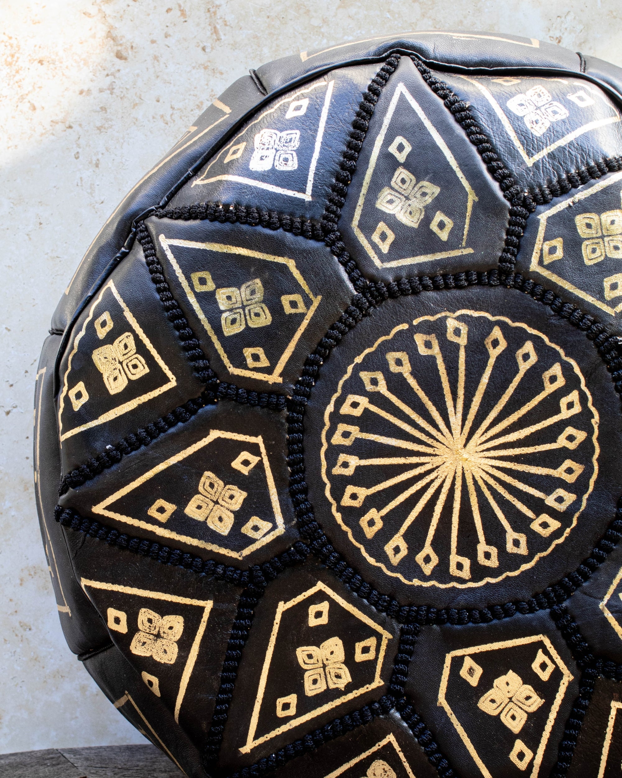 Close up of gold embroidery on black leather pouf