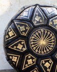 Close up of gold embroidery on black leather pouf