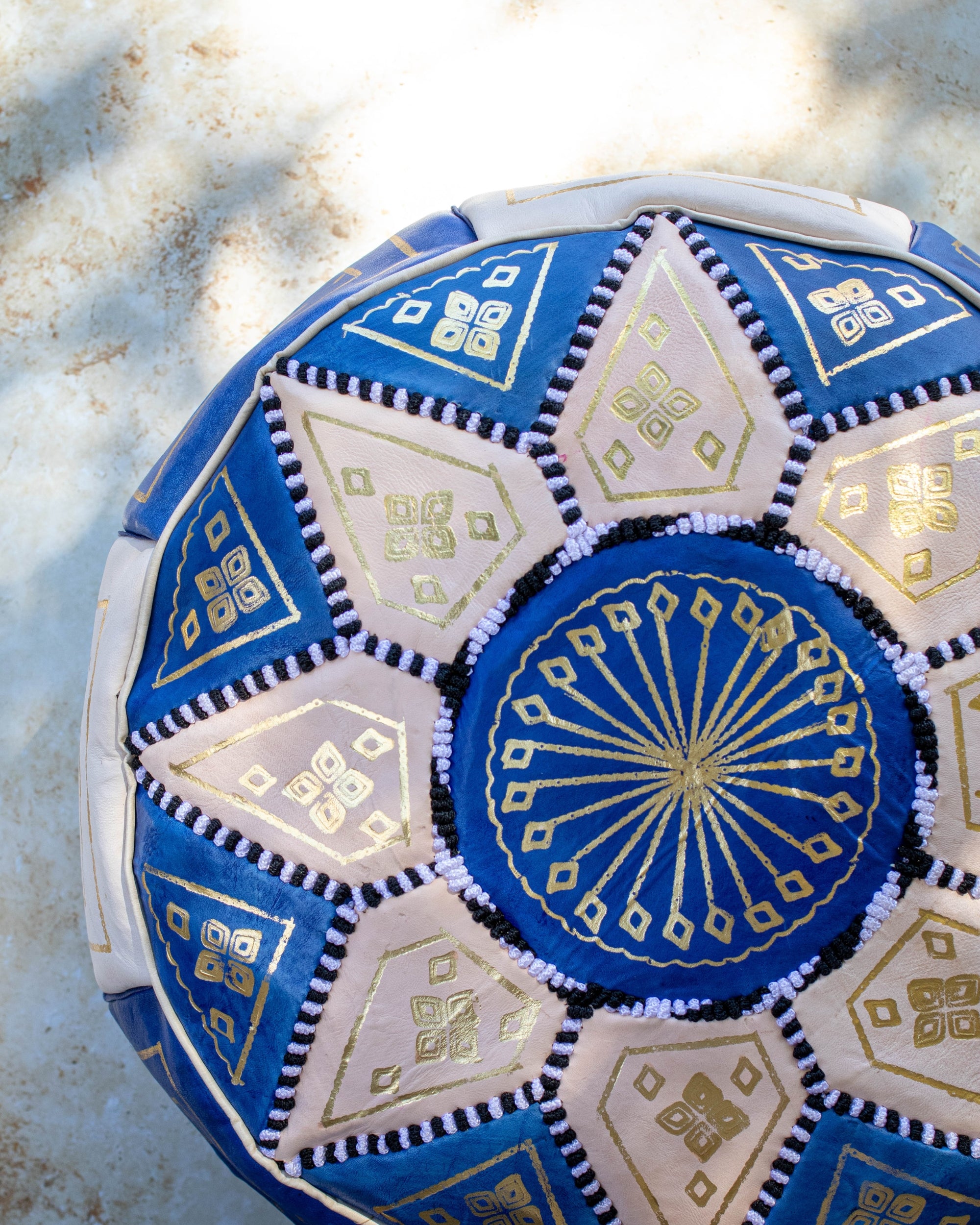 Close up of gold embroidery on blue and cream leather pouf
