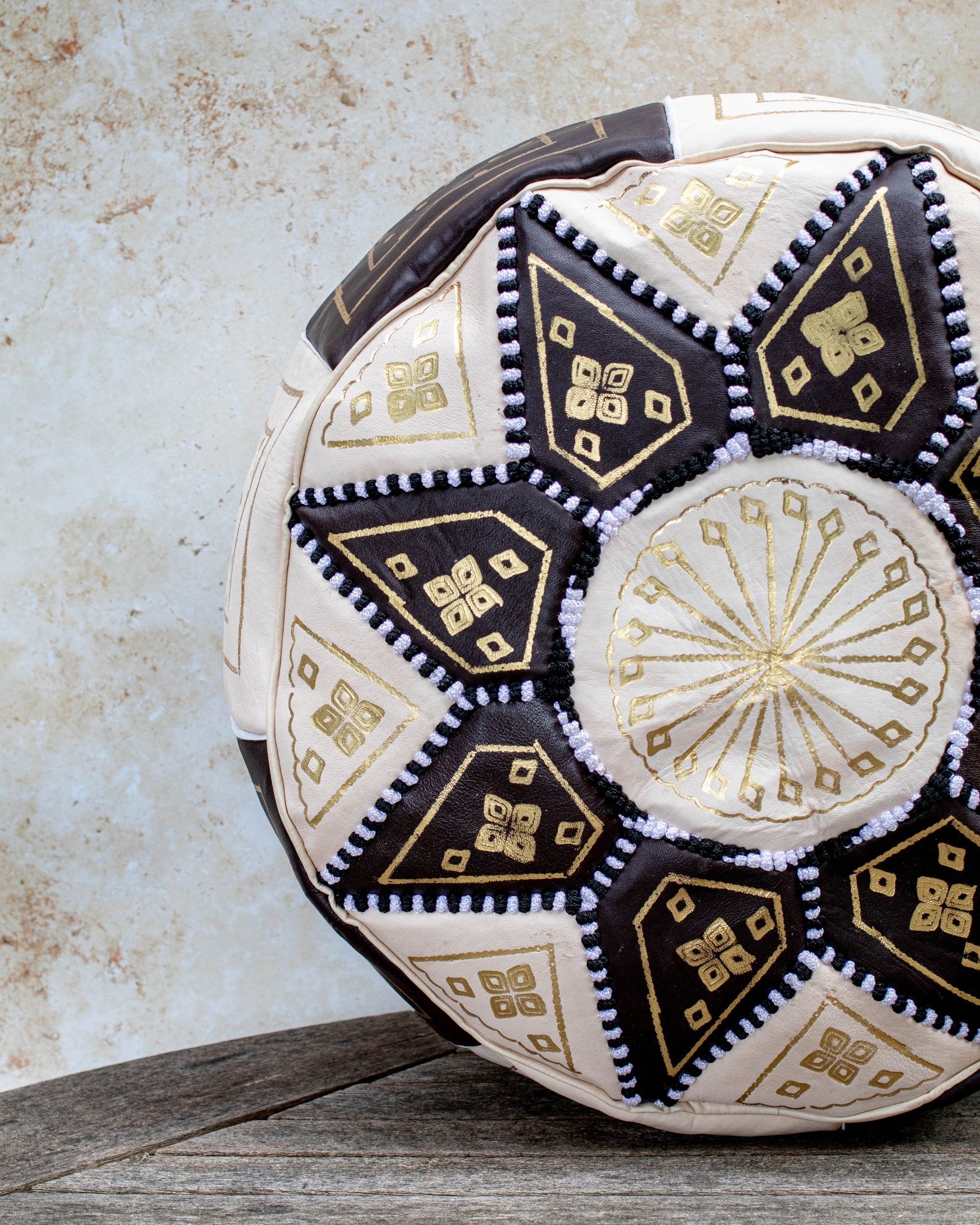 Close up of gold embroidery on brown and cream leather pouf