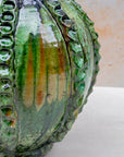 Glossy green ceramic vase on neutral background
