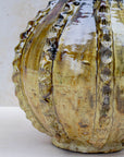 Glossy ochre and bronze ceramic vase on neutral background