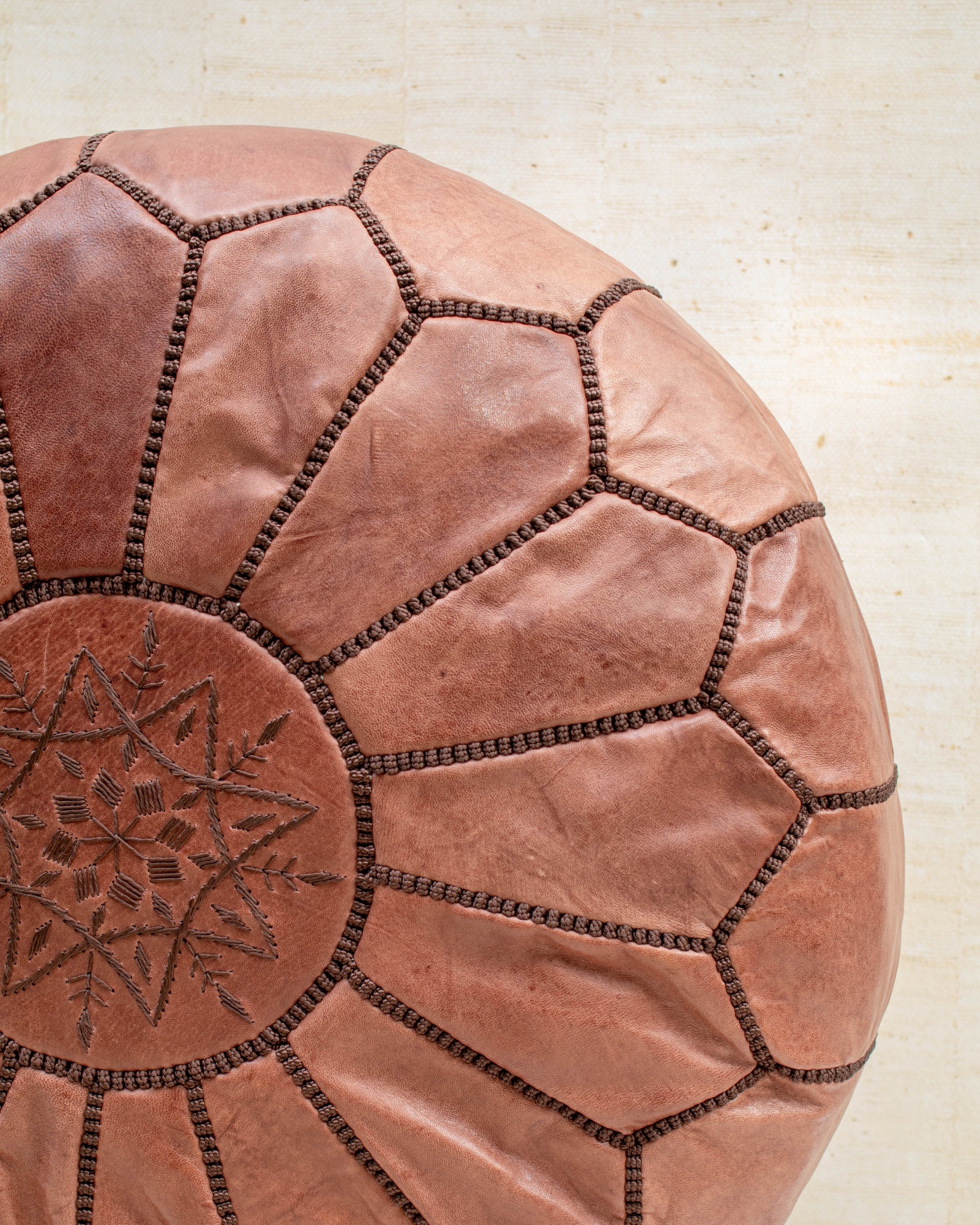 Hand-stitched detail — tan leather pouf