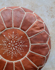 Natural tan Moroccan pouf styled as ottoman in living room