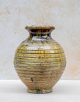 Ochre ceramic vase styled with flowers on neutral background