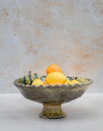 Ochre pedestal bowl filled with lemons on neutral background
