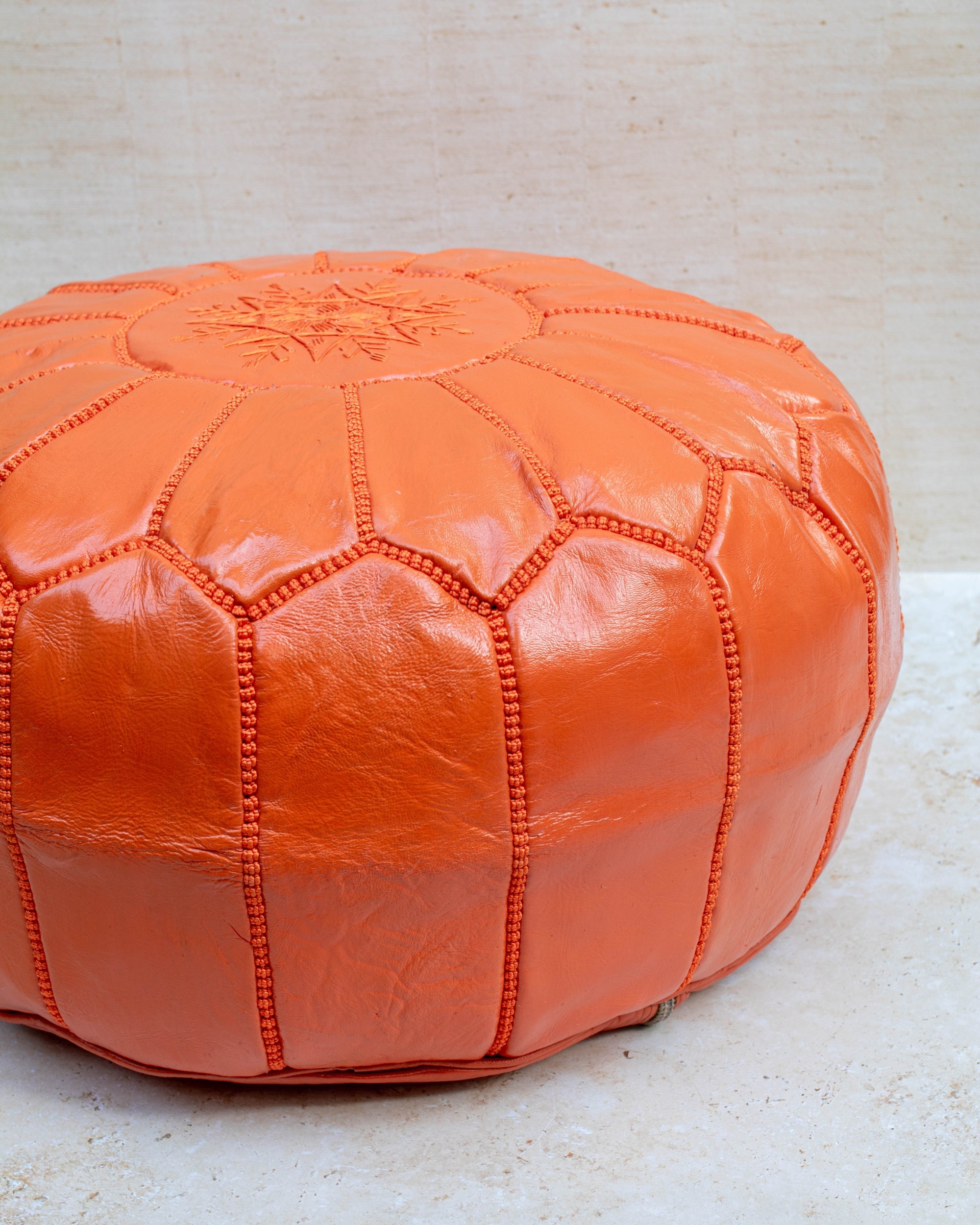 Orange pouf styled in living room as ottoman