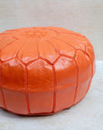 Orange pouf styled in living room as ottoman