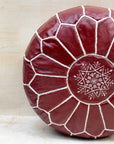 Red leather pouf with white embroidery on a light background