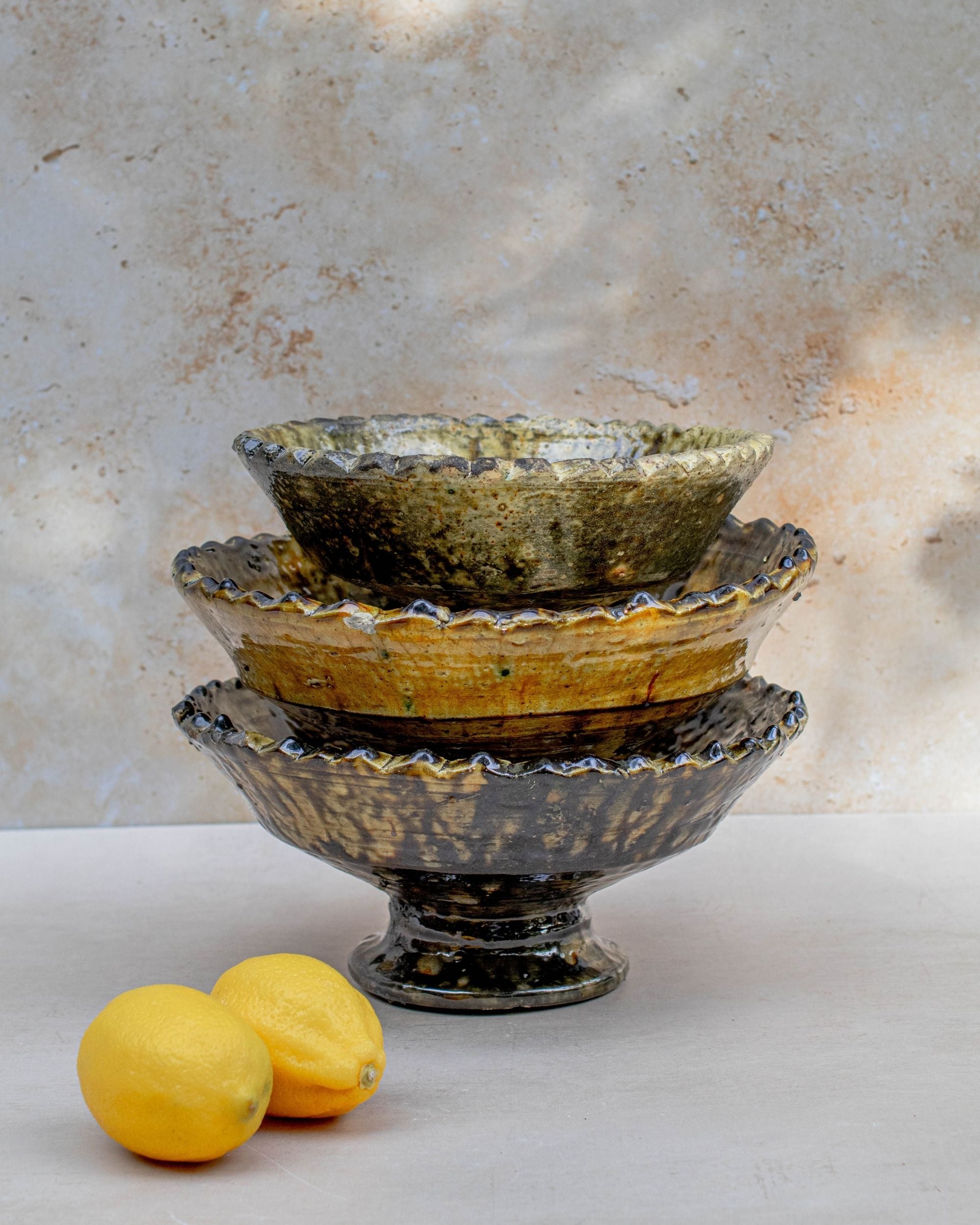 Stacked Tamegroute ochre pedestal bowls showing handmade glaze variations