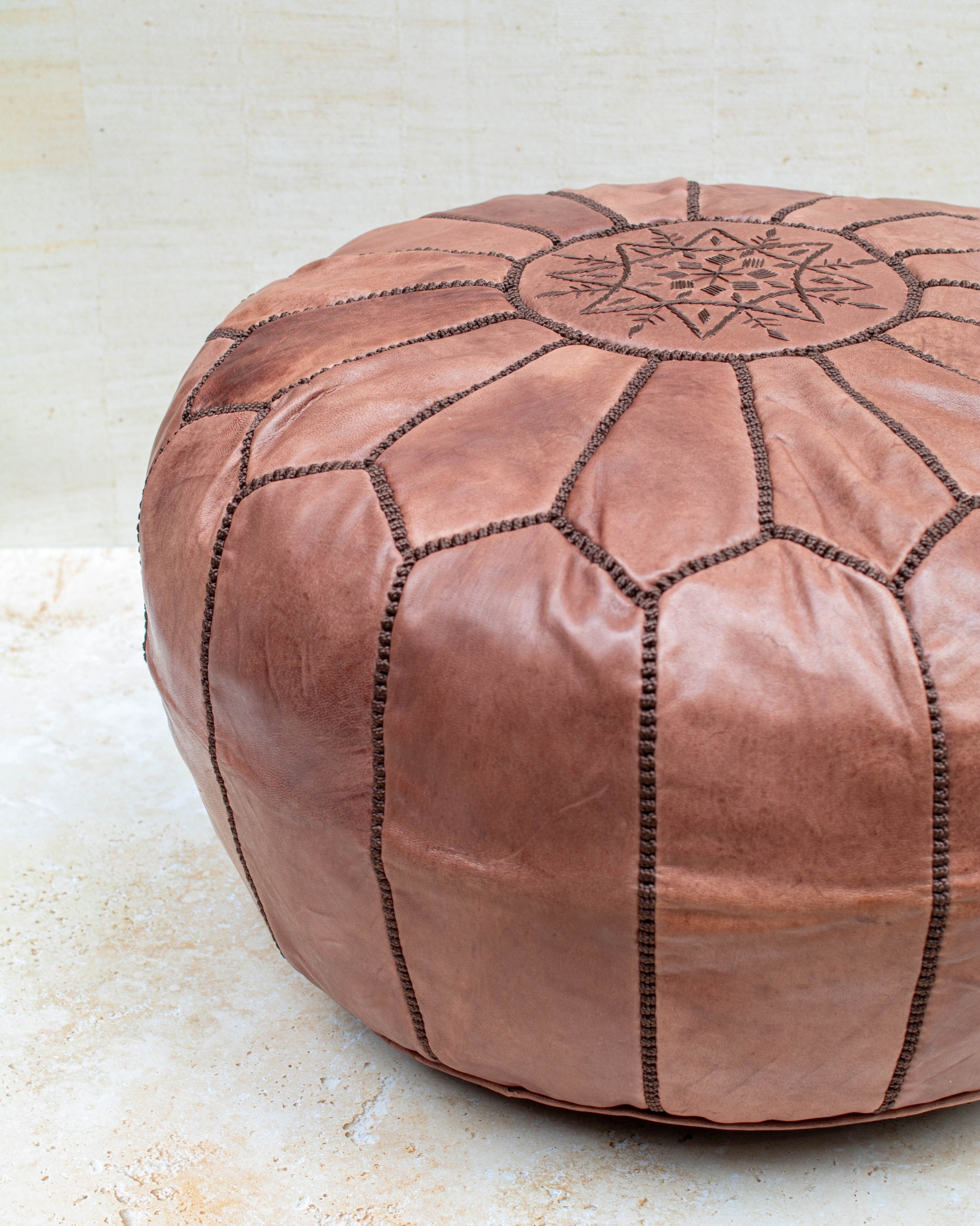Tan leather pouf styled in living room
