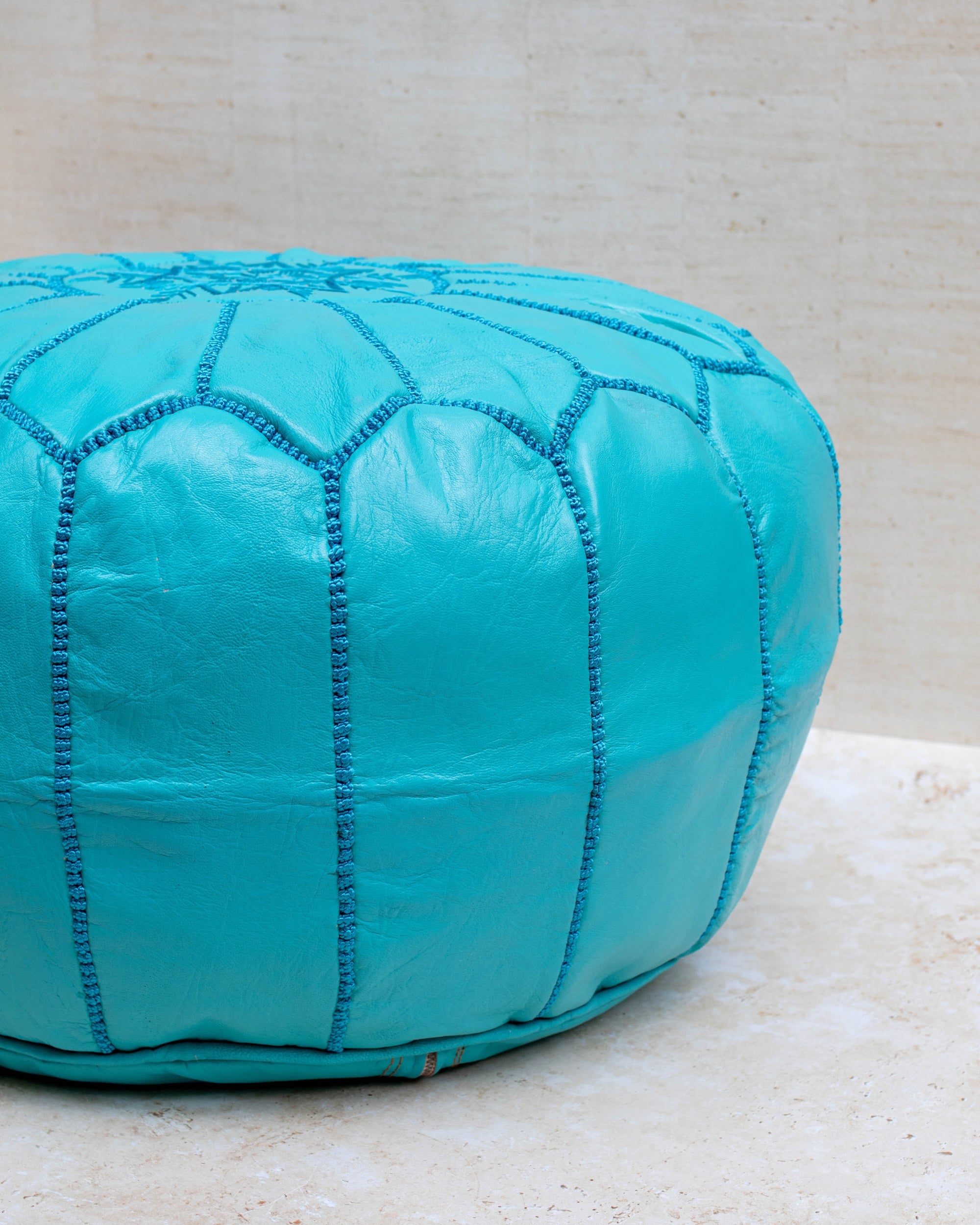 Turquoise pouf styled in living room as ottoman