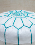 White and turquoise pouf styled in living room as ottoman