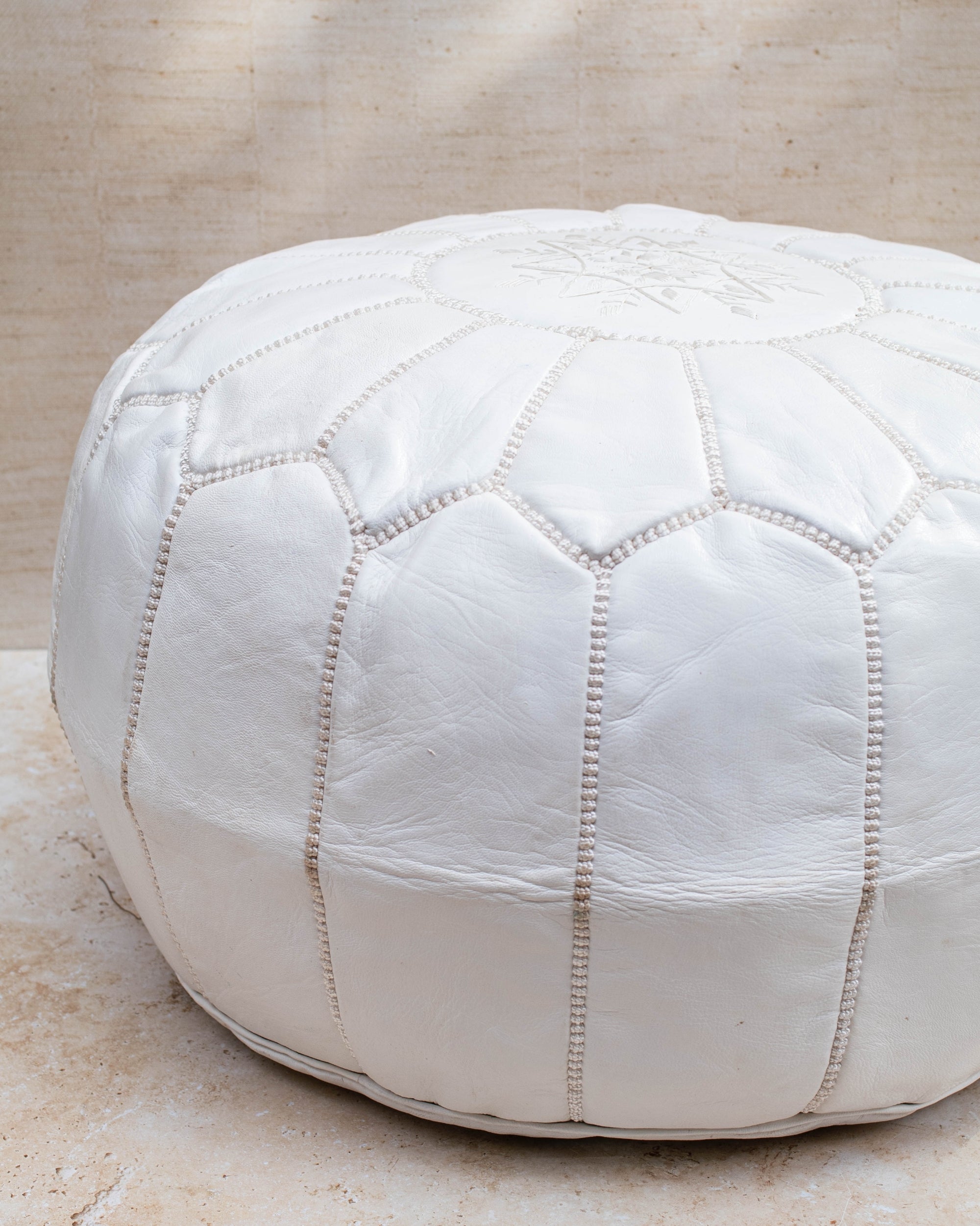 White leather pouf styled as ottoman in living room