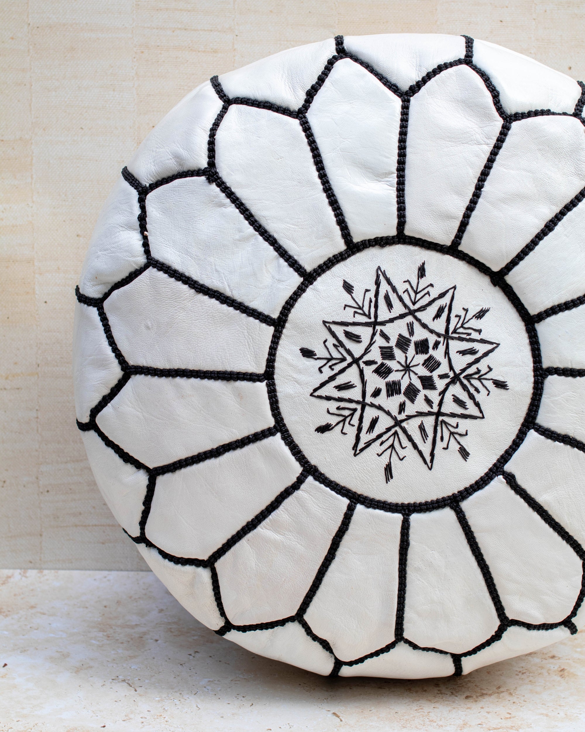 White leather pouf with black hand-stitching – embroidery detail close-up