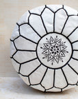 White leather pouf with black hand-stitching – embroidery detail close-up