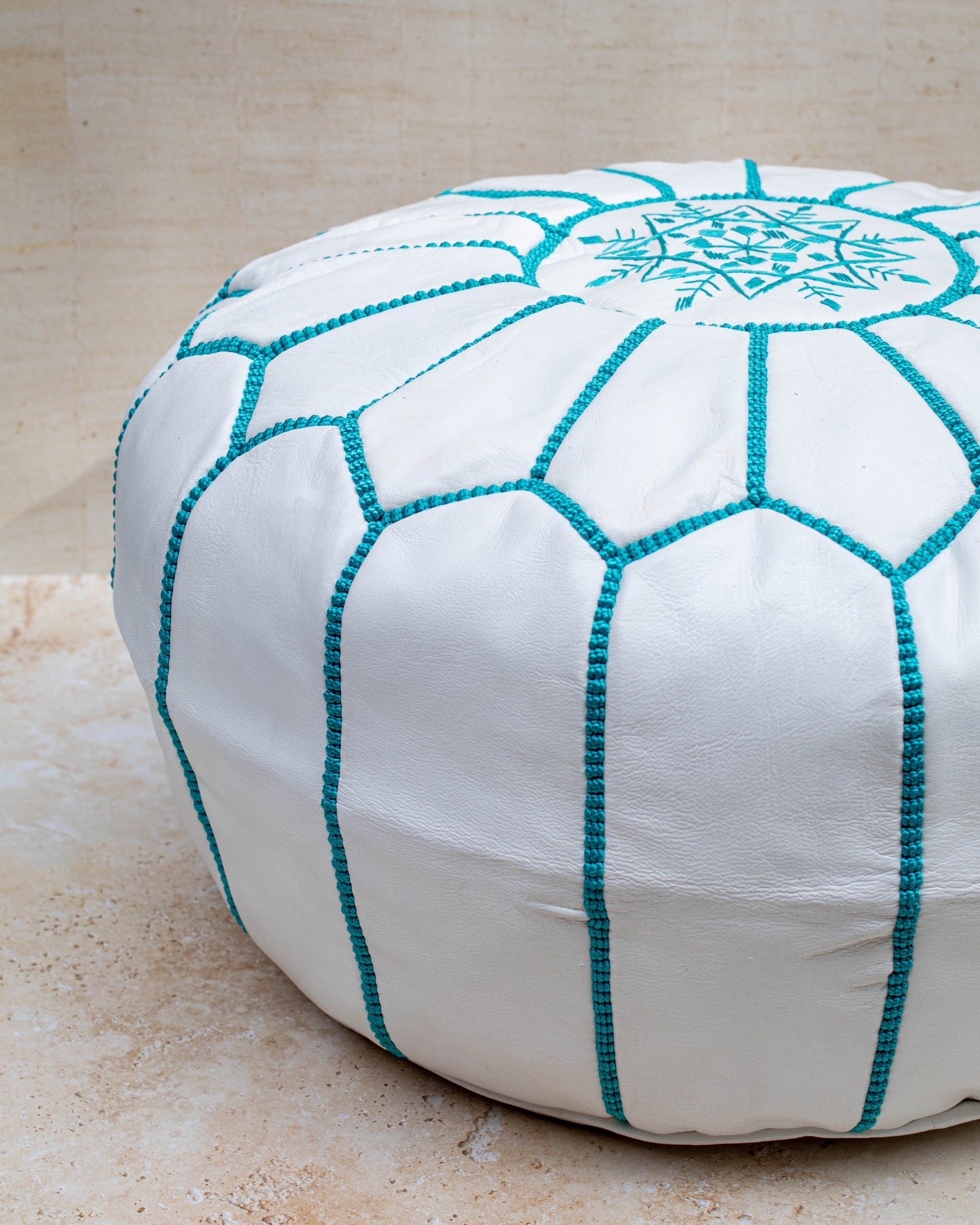 White leather pouf with turquoise hand-stitching – embroidery detail close-up
