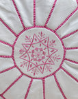 White with pink stitching pouf styled in living room as ottoman