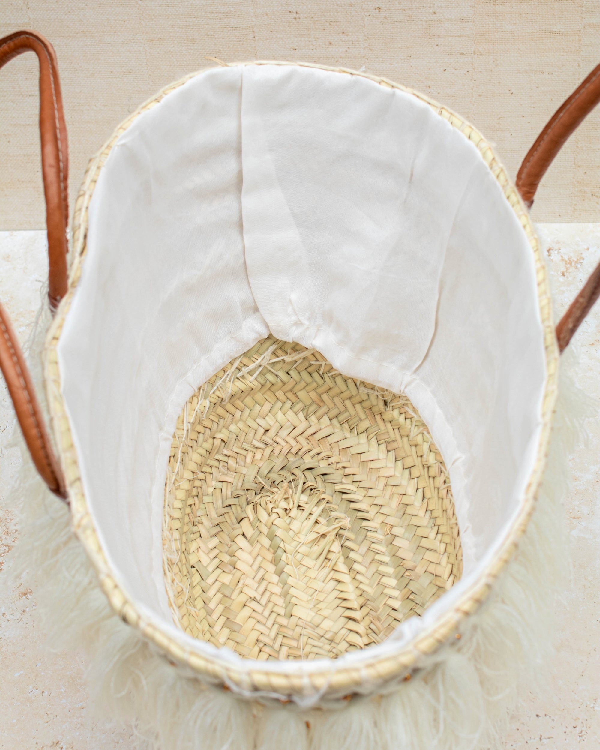 Wicker basket with white lining on a light wooden surface