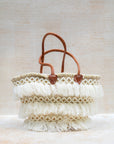 Woven bag with leather handles and tassels on a light background