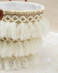 Woven basket with tassels and beads on a light background