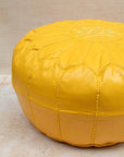 Yellow pouf styled in living room as ottoman