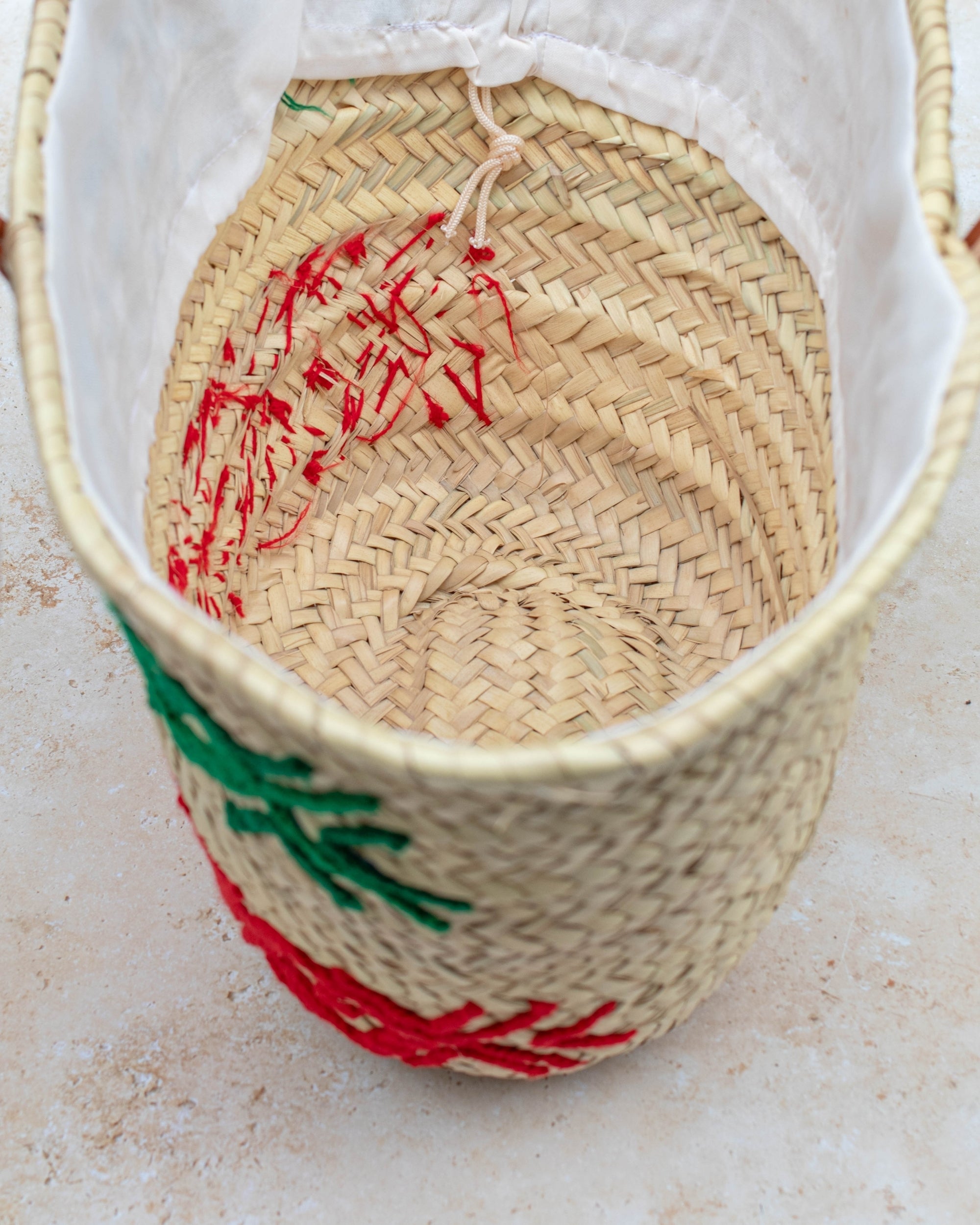 Palm leaf basket with green and red embroidery – close-up of stitching