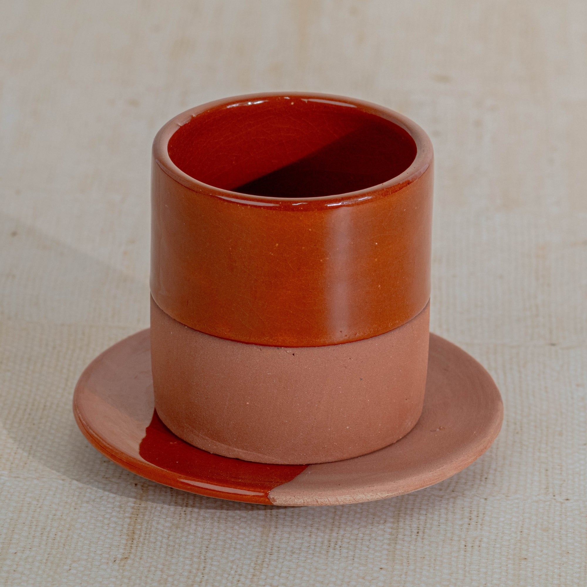 Ceramic cup and saucer set with a gradient color on a textured beige background