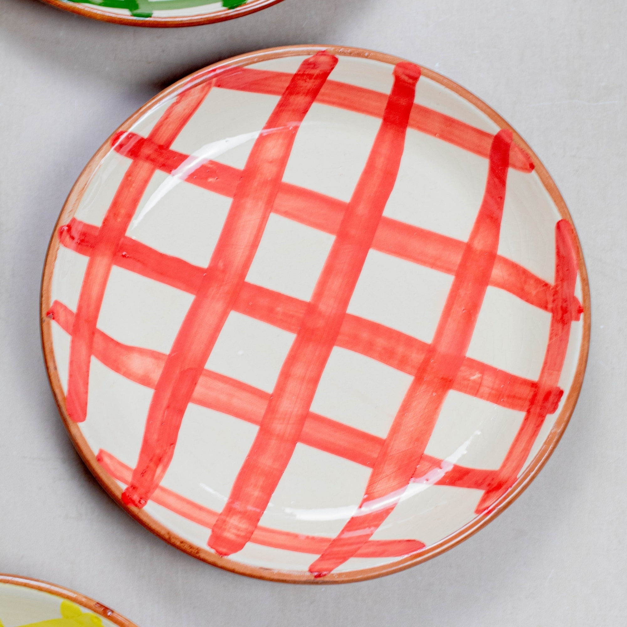 Ceramic plate with red grid pattern on a gray surface