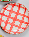 Ceramic plate with red grid pattern on a gray surface