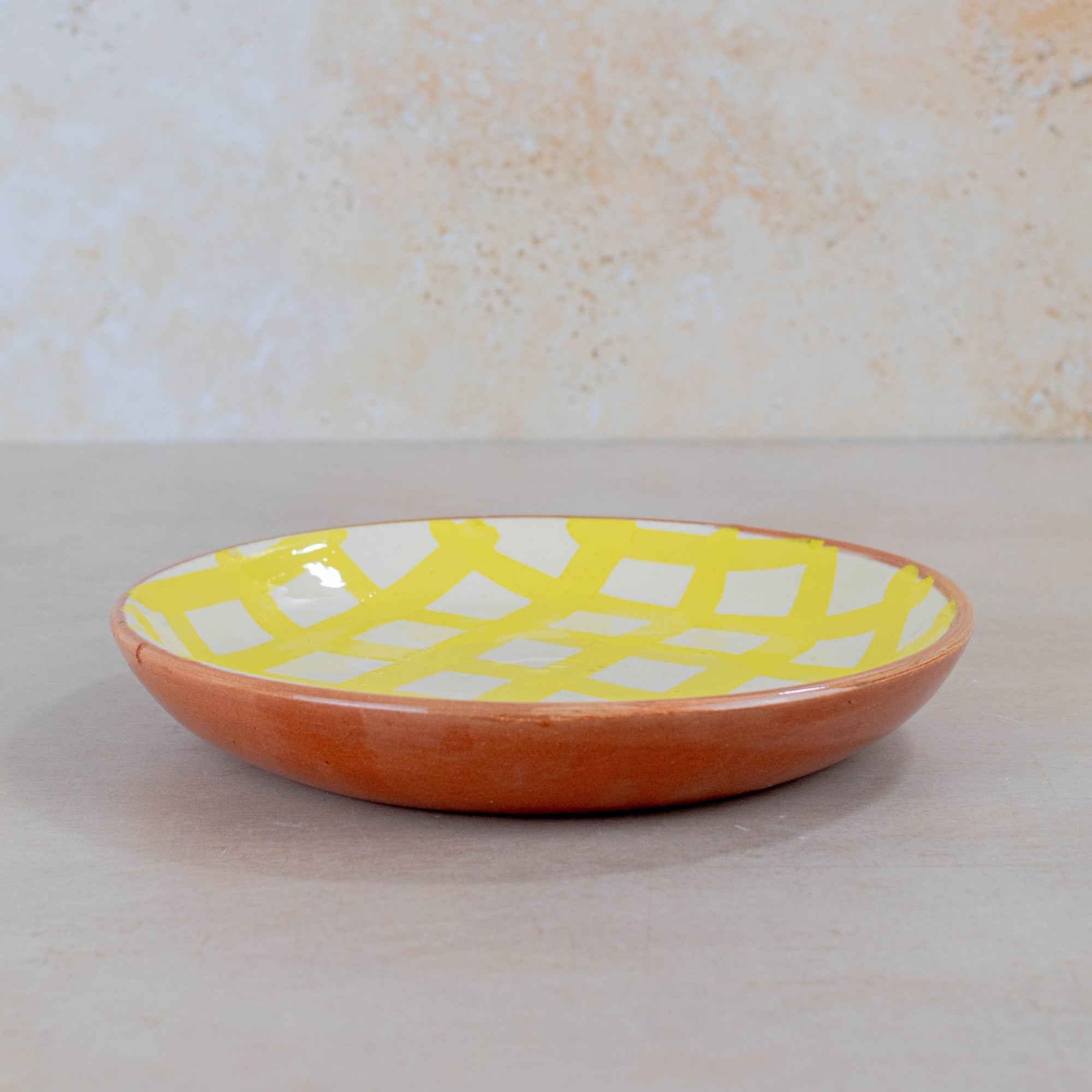 Ceramic plate with a yellow and white geometric pattern on a beige background
