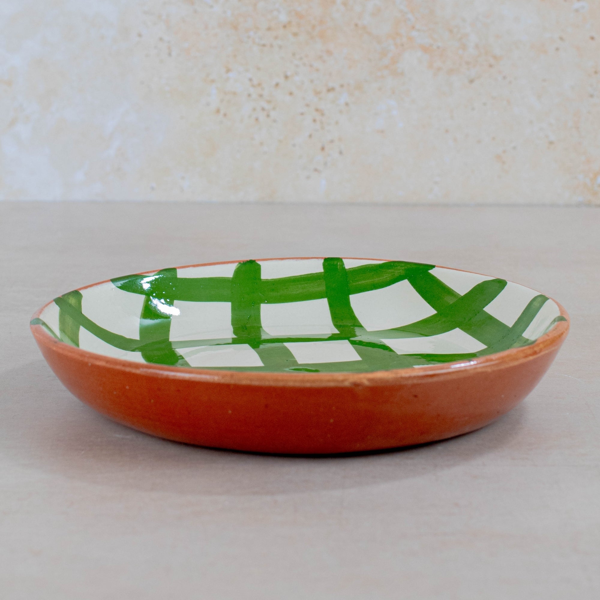 Ceramic plate with green and white pattern on a beige background