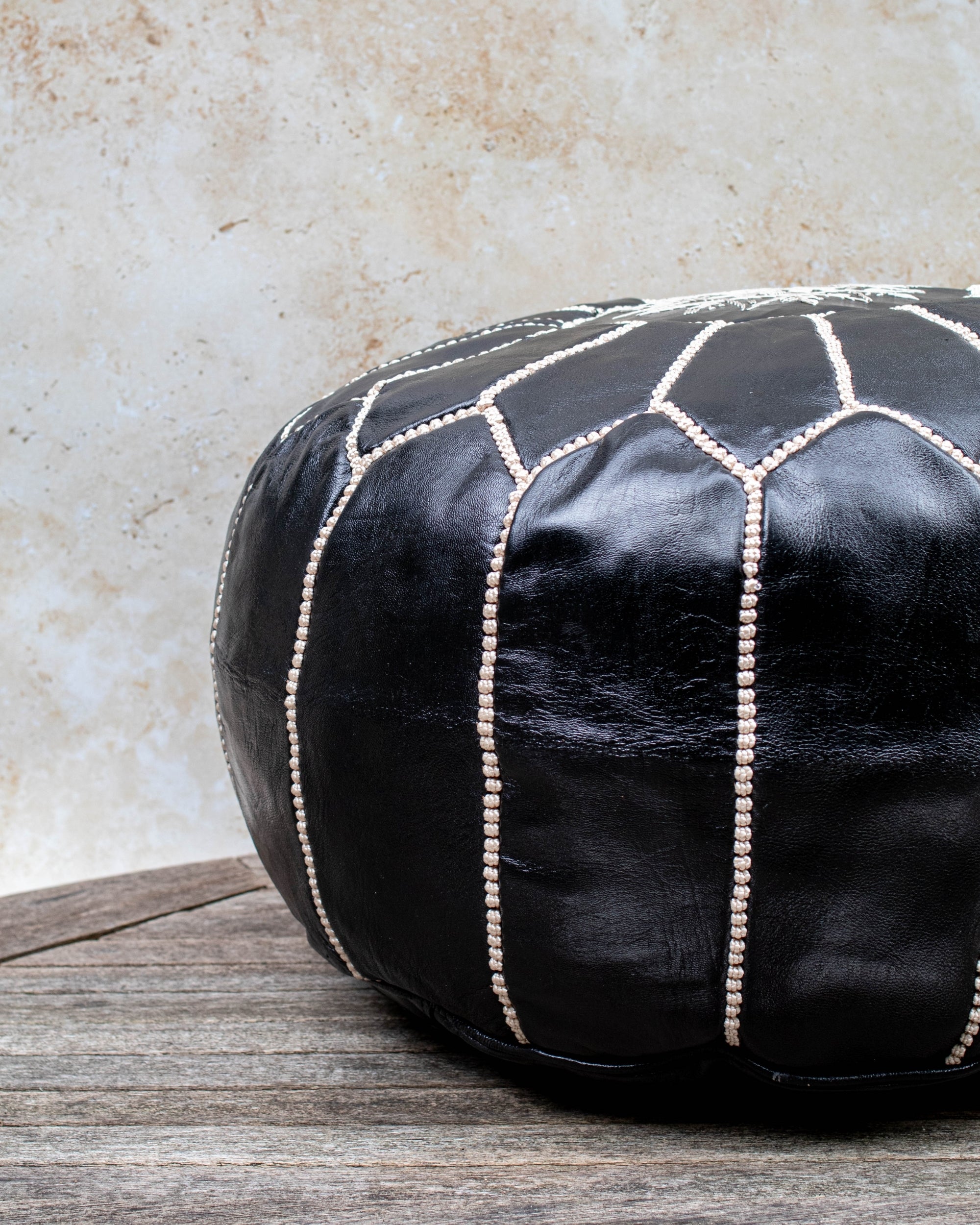 Black and beige stitched pouf styled in living room