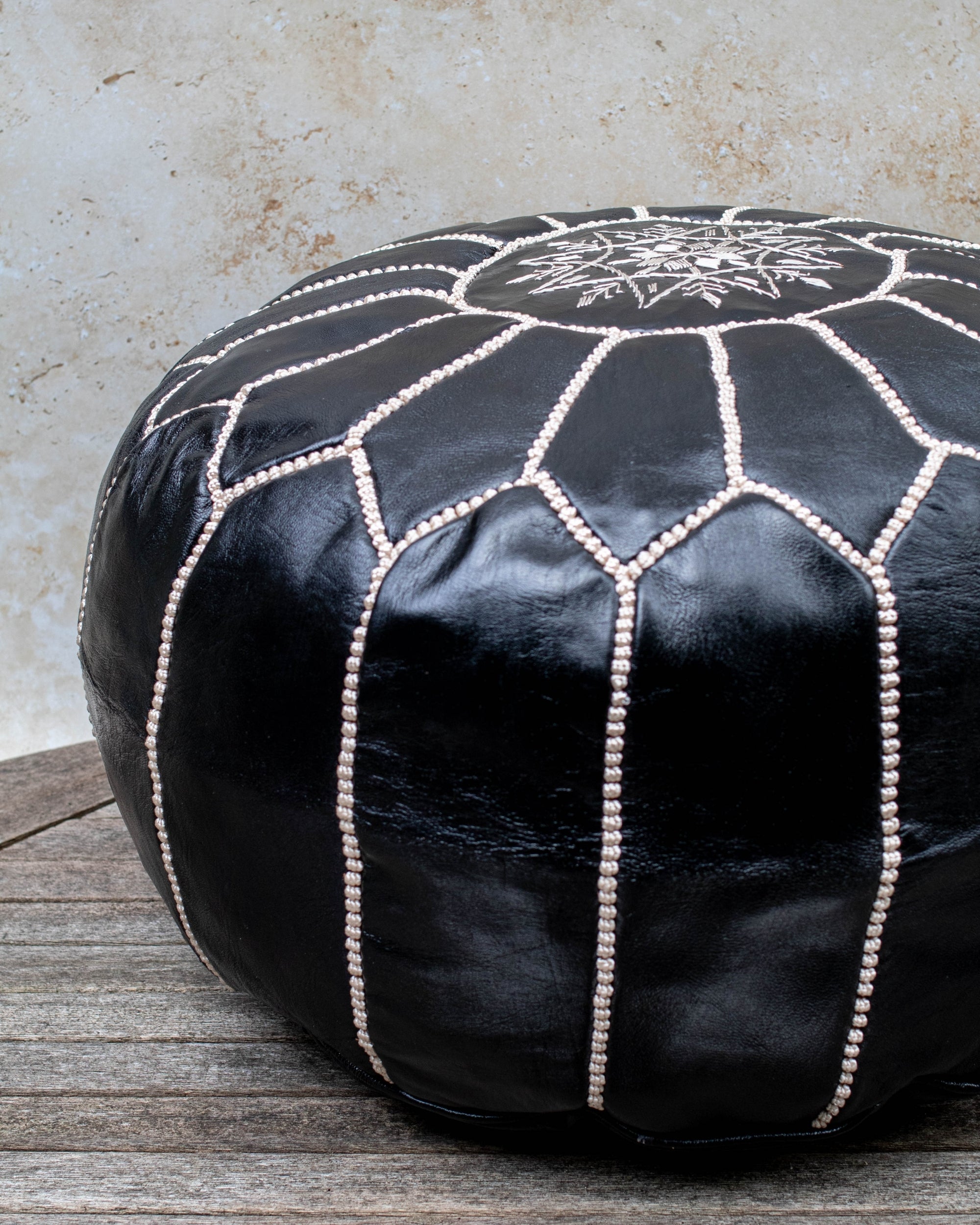 Black leather pouf beige stitching detail close up