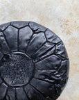 Black pouf styled in living room as ottoman