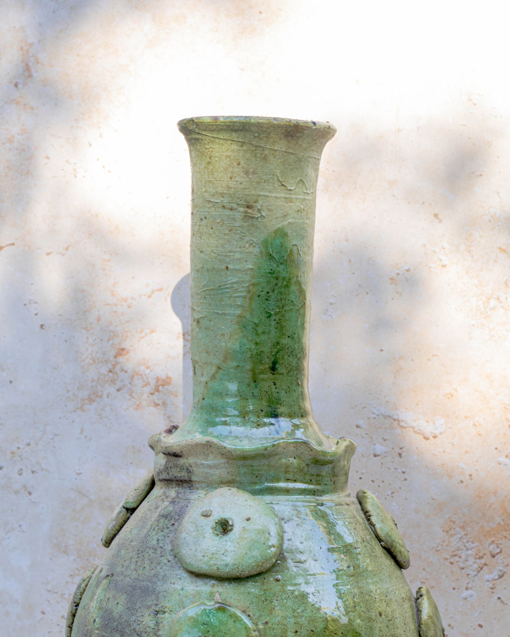 Close-up of raised circular detailing on pale green Moroccan pottery vase