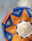 Close up of gold embroidery on blue and orange leather pouf