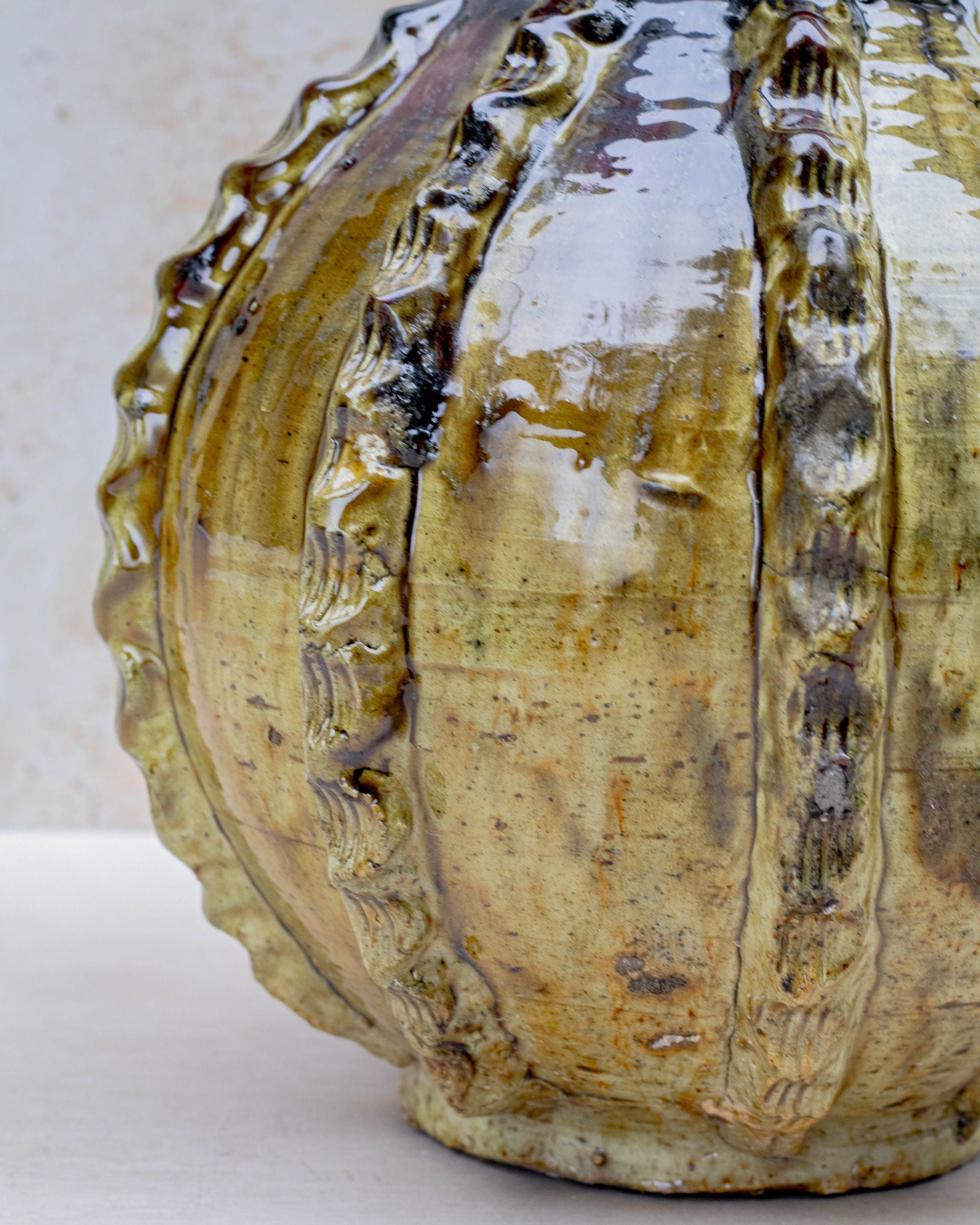 Glossy ochre and bronze ceramic vase on neutral background