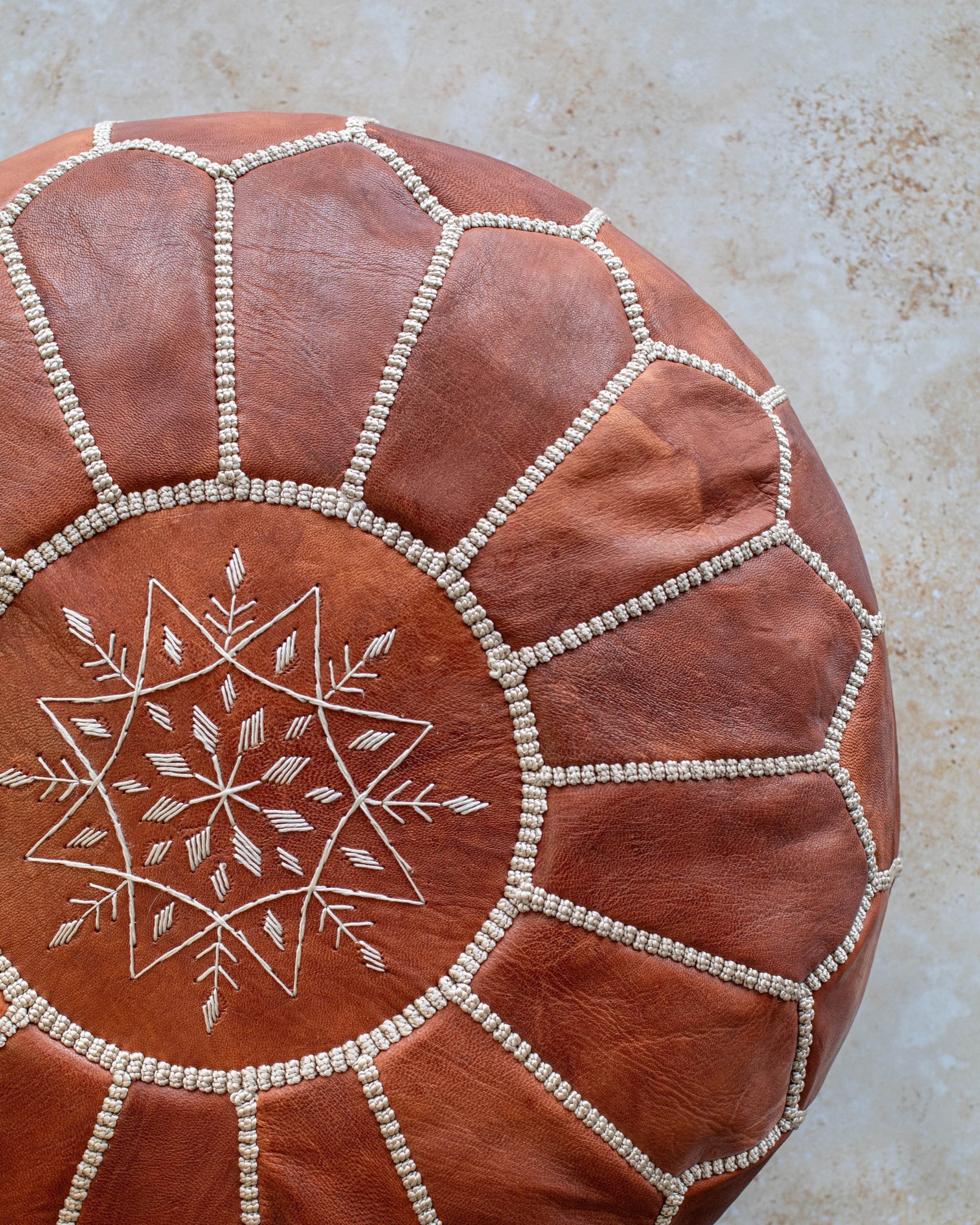 Natural tan Moroccan pouf styled as ottoman in living room
