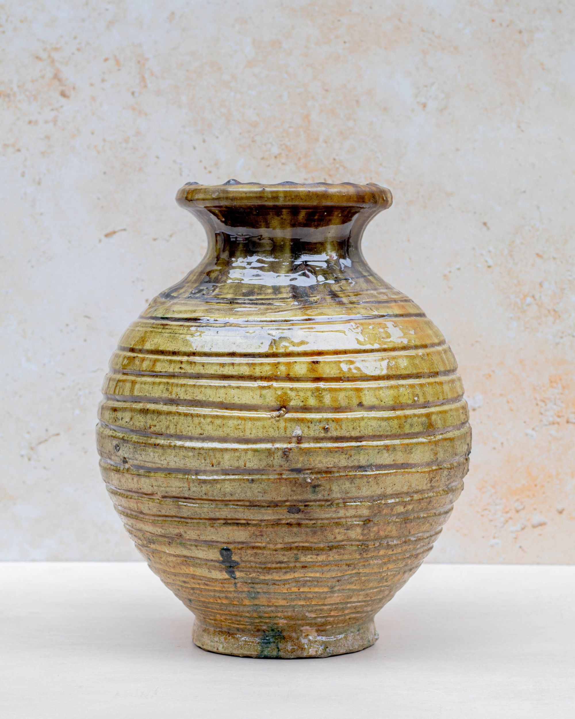 Ochre ceramic vase styled with flowers on neutral background