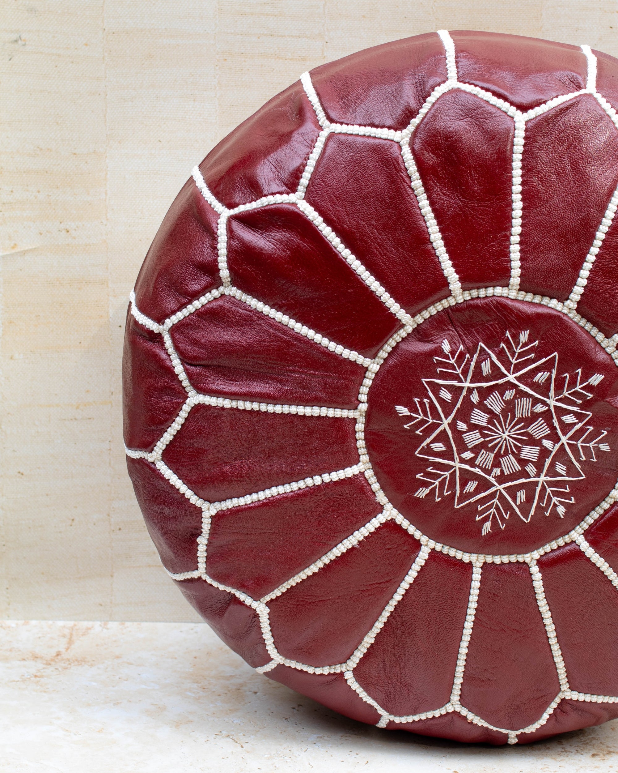Red leather pouf with white embroidery on a light background